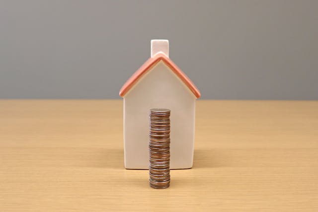 a stack of coins in front of a small model house