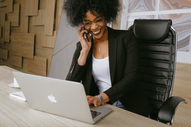 woman in black blazer on the phone smiling