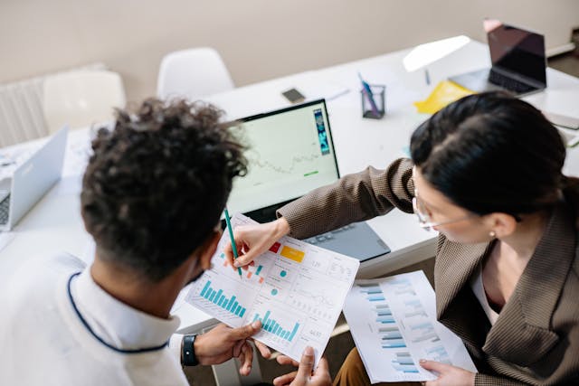 two people looking at papers with graphs on them